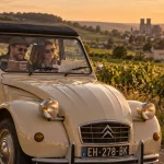 Visiter Reims 2CV : 2CV beige près des vignes, golden hour