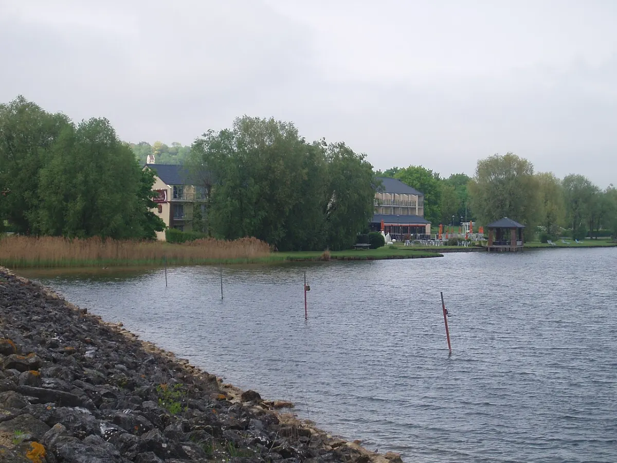 Les rives du lac de l'Ailette à Chamouille, digue de pierre au premier plan et bâtiments au bord de l'eau